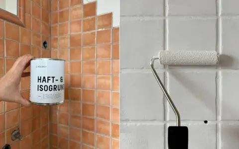 Vorbereitung zum Fliesenfärben: Eine Hand hält eine Dose Haftgrund, während ein Roller weiße Farbe auf Fliesen aufträgt.