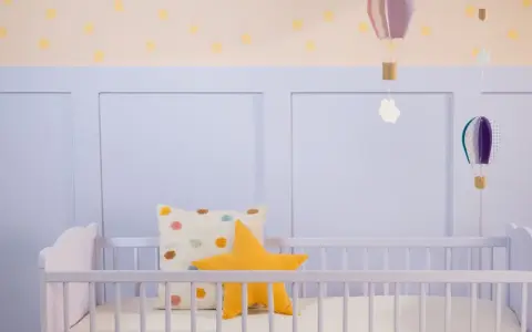 Ein frisch gestrichenes Kinderbett in zartem Lila, dekoriert mit bunten Kissen und schwebenden Heißluftballons.
