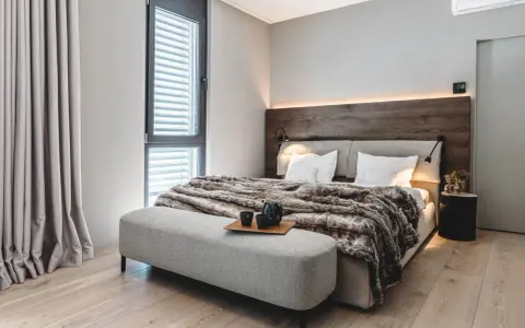 Gemütliches Schlafzimmer mit Holzbettkopfteil, flauschiger Decke und Sitzbank. Tolle zimmer inspo für ein modernes Ambiente.
