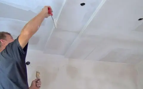 Mann trägt Grundierung auf Rigips-Decke auf.
