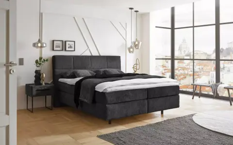 Ein modernes Schlafzimmer mit einem dunklen Boxspringbett ja oder nein? Helle Wände, Holzboden und ein Fenster mit Stadtblick.