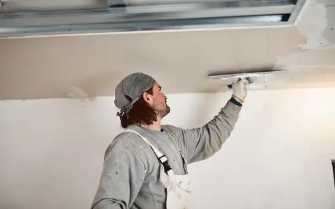 Handwerker verputzt Decke, inspiriert von modernen Deckenverkleidung Ideen für ein glattes Finish.