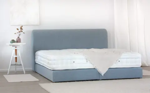 Ein Boxspringbett mit blauem Stoffbezug und weißer Matratze. So wird ein Boxspringbett geliefert: zerlegt und einfach aufzubauen.