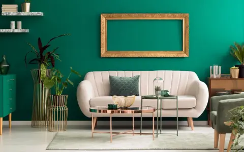 Ein helles Sofa und goldene Akzente harmonieren perfekt mit der petrolfarbenen Wand. Welche Farbe passt zu petrol? Hier sehen wir eine elegante Kombination.
