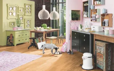 Helle Wandfarbe passt gut zu Buche-Boden und grüner Kommode. Ein Hund frisst aus Napf.