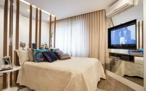 Ein modernes Schlafzimmer mit einem eleganten Bett, vielen Kissen und einem versteckten TV im Spiegel-Schrank.