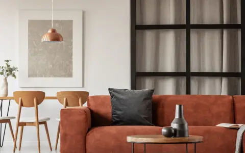 Gemütliches Wohnzimmer mit orangefarbenem Sofa, Holztisch und Stühlen. Tolle inneneinrichtung ideen für ein warmes Ambiente.