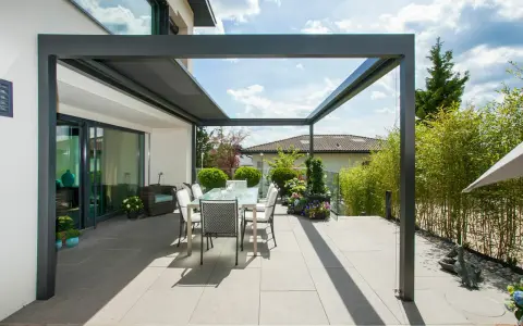 Moderne Terrassenbeschattung Ideen: Ein Essbereich unter einer Pergola mit Glasdach, umgeben von Bambus und Blumen.