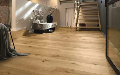 Ein heller Flur mit Treppe und Sitzbank. Der Boden ist aus echtem **Vollholz**, das Wärme und Natürlichkeit ausstrahlt.