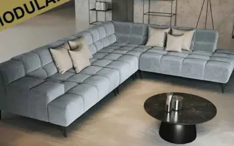 Moderne, graue Eckcouch mit Kissen. Die ottomane bedeutung als flexibler Sitzmöbel-Bestandteil wird hier durch das modulare Design unterstrichen.