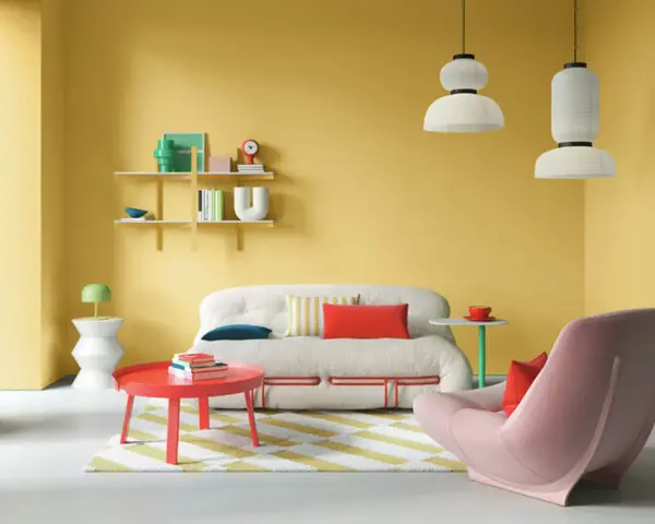 Lebendige wohnraumgestaltung farben: gelbe Wände, ein flauschiges Sofa, ein roter Couchtisch und ein rosa Sessel schaffen eine fröhliche Atmosphäre.