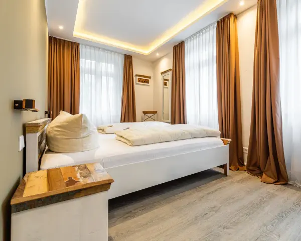 Gemütliches Schlafzimmer mit Doppelbett, Sitzsack und rustikalem Nachttisch. Die Einrichtung der Ferienwohnung ist modern und einladend.