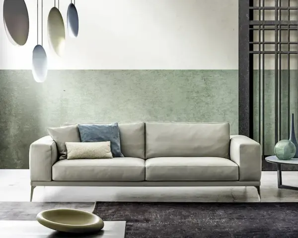 Modernes Wohnzimmer mit hellem Sofa, grüner Wand und stilvollem farbkonzept. Hängende Lampen und dekorative Vasen ergänzen das Ambiente.