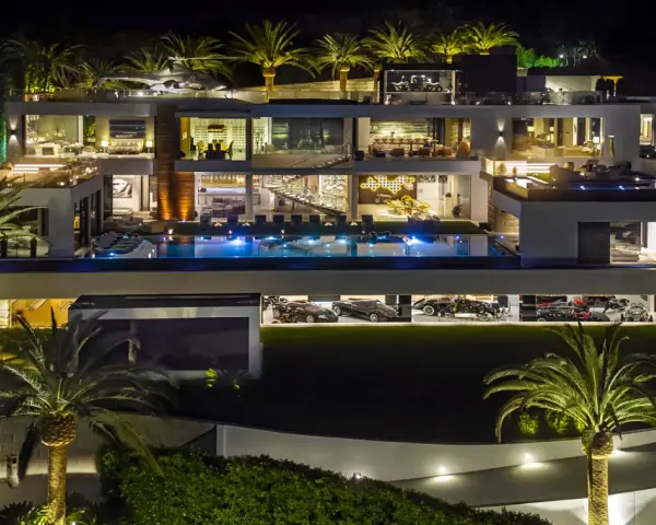 Luxuriöse Villa bei Nacht mit Pool, Palmen und einer Garage voller teuerstes Holz der Welt.