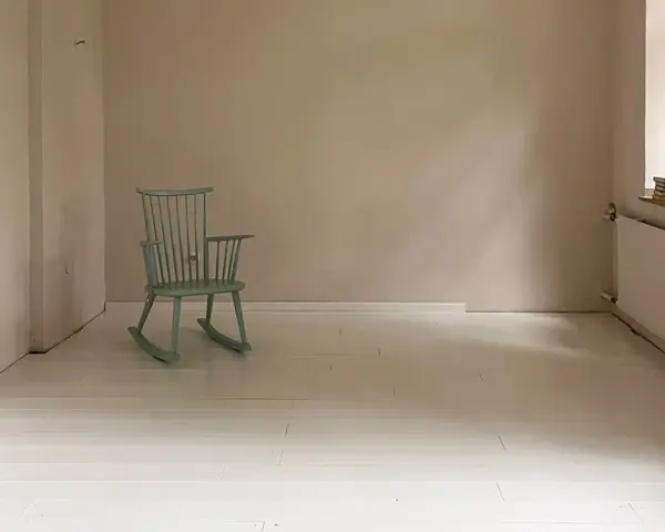 Ein hell gestrichener holzboden mit einer mintgrünen Schaukelstuhl.
