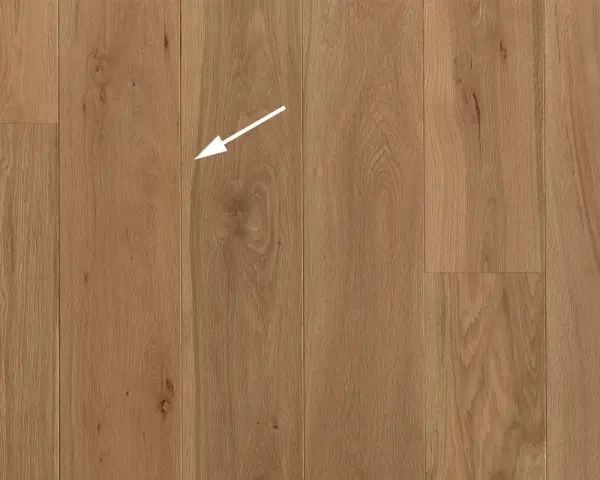 Holzboden mit natürlicher Maserung. Ein weißer Pfeil zeigt auf eine kleine Astloch-Stelle im splint holz.