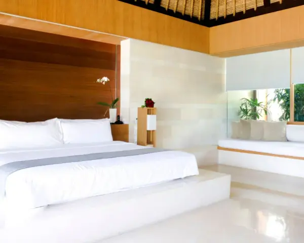 Luxuriöses Schlafzimmer mit einem großen weißen Bett, das den Unterschied zwischen einem King und Queen Bett verdeutlicht. Holzakzente und viel Licht.