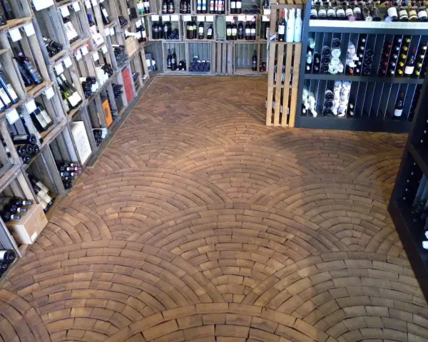 Ein Weinladen mit Regalen voller Flaschen und einem Boden aus Hirnholz, das wie ein Mosaik aus Holzscheiben verlegt ist.
