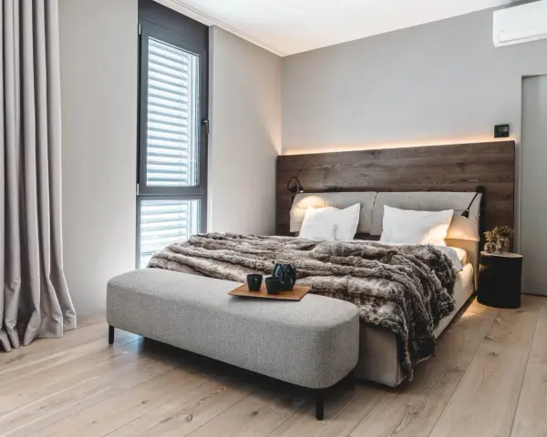 Gemütliches Schlafzimmer mit Holzbettkopfteil, flauschiger Decke und Sitzbank. Tolle zimmer inspo für ein modernes Ambiente.