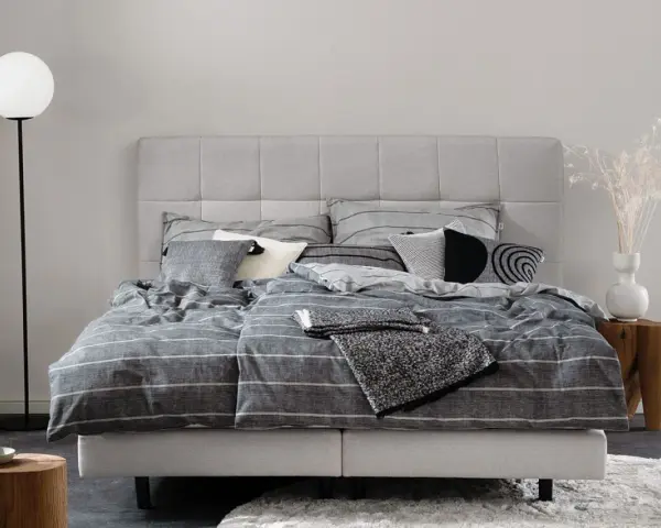Stilvolle Schlafzimmer Ideen mit einem grauen Boxspringbett, gestreifter Bettwäsche und modernen Akzenten.