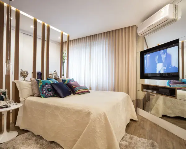 Ein modernes Schlafzimmer mit einem eleganten Bett, vielen Kissen und einem versteckten TV im Spiegel-Schrank.