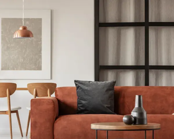 Gemütliches Wohnzimmer mit orangefarbenem Sofa, Holztisch und Stühlen. Tolle inneneinrichtung ideen für ein warmes Ambiente.