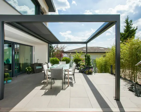 Moderne Terrassenbeschattung Ideen: Ein Essbereich unter einer Pergola mit Glasdach, umgeben von Bambus und Blumen.