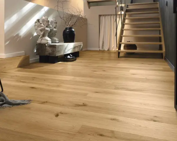 Ein heller Flur mit Treppe und Sitzbank. Der Boden ist aus echtem **Vollholz**, das Wärme und Natürlichkeit ausstrahlt.