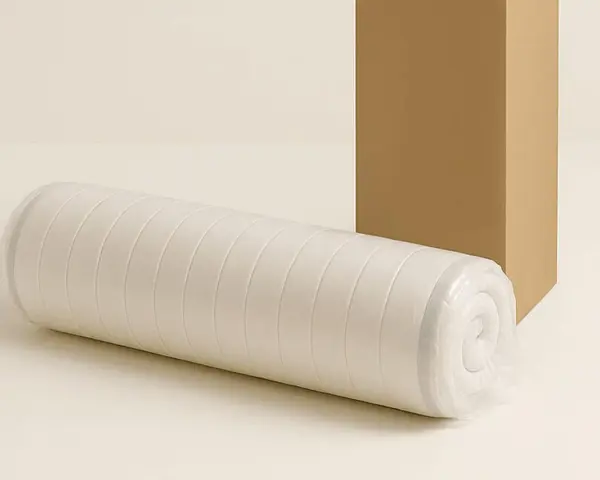 Gerollt und verpackt: So werden Matratzen geliefert. Eine aufgerollte Matratze liegt neben einem Karton.