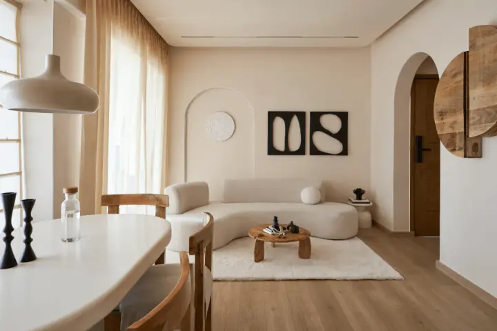 Ein gemütliches wabi sabi interior mit geschwungener Couch, Holztisch und warmen Erdtönen.