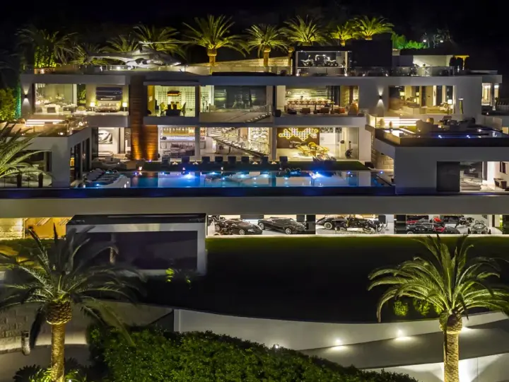 Luxuriöse Villa bei Nacht mit Pool, Palmen und einer Garage voller teuerstes Holz der Welt.
