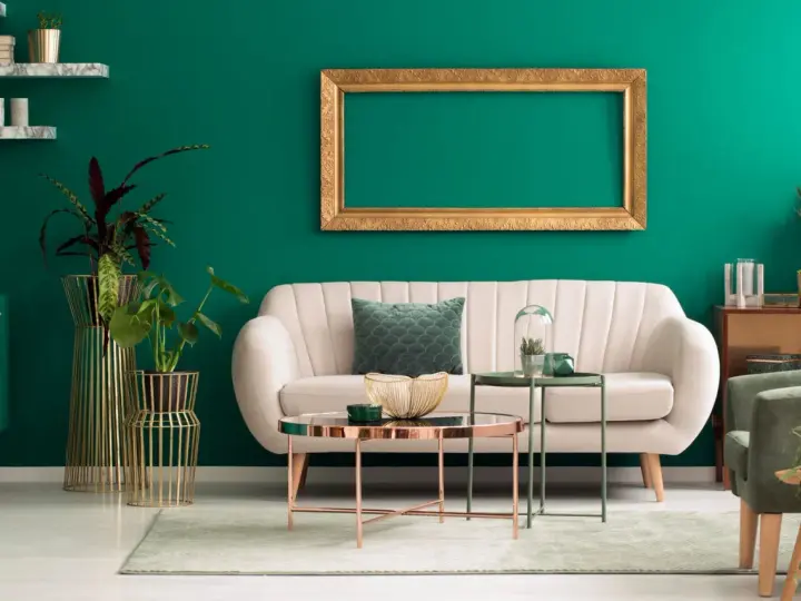 Ein helles Sofa und goldene Akzente harmonieren perfekt mit der petrolfarbenen Wand. Welche Farbe passt zu petrol? Hier sehen wir eine elegante Kombination.
