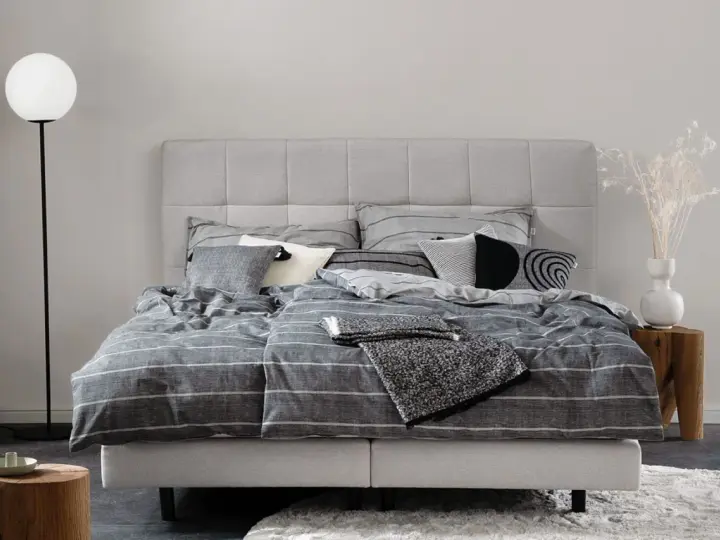 Stilvolle Schlafzimmer Ideen mit einem grauen Boxspringbett, gestreifter Bettwäsche und modernen Akzenten.