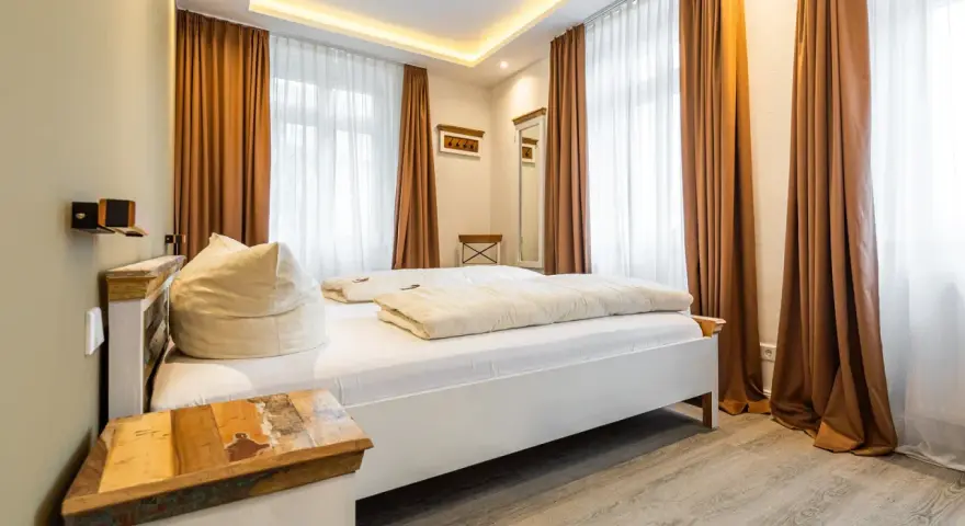 Gemütliches Schlafzimmer mit Doppelbett, Sitzsack und rustikalem Nachttisch. Die Einrichtung der Ferienwohnung ist modern und einladend.