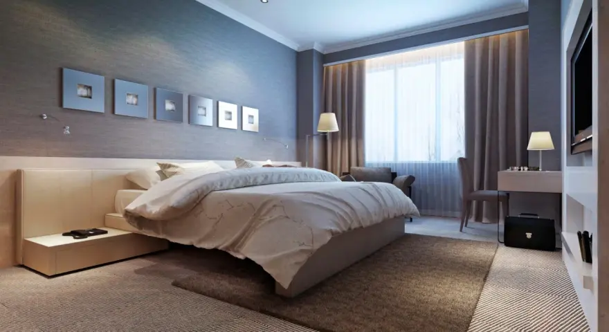 Modernes Schlafzimmer mit einem bequemen Bett, das wie ein wasserbett oder boxspringbett wirkt. Dekorative Wandbilder und ein Schreibtisch mit Lampe.