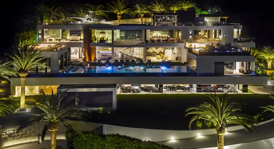 Luxuriöse Villa bei Nacht mit Pool, Palmen und einer Garage voller teuerstes Holz der Welt.