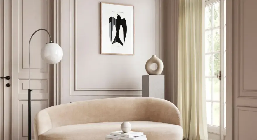 Ein stilvolles Wohnzimmer in greige farbe mit einem geschwungenen Sofa, einem modernen Lampenschirm und einem abstrakten Vogelbild.