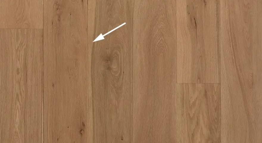 Holzboden mit natürlicher Maserung. Ein weißer Pfeil zeigt auf eine kleine Astloch-Stelle im splint holz.