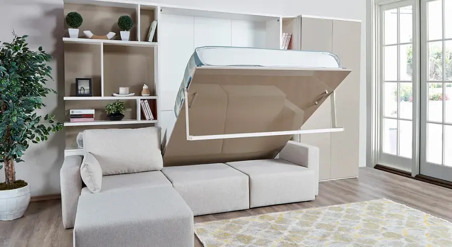 Ein verstecktes Bett im Wohnzimmer wird aus einem Schrank herausgeklappt. Daneben ein Sofa und ein Bücherregal.