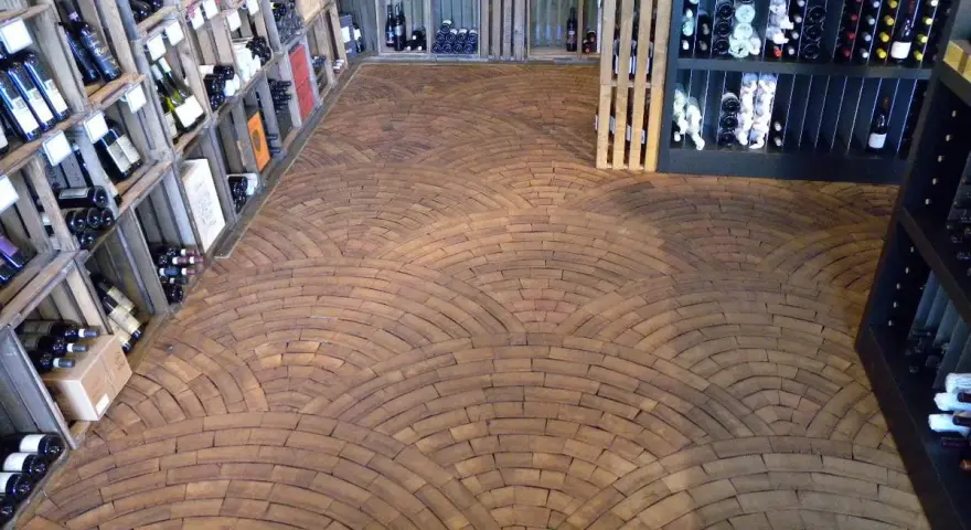 Ein Weinladen mit Regalen voller Flaschen und einem Boden aus Hirnholz, das wie ein Mosaik aus Holzscheiben verlegt ist.