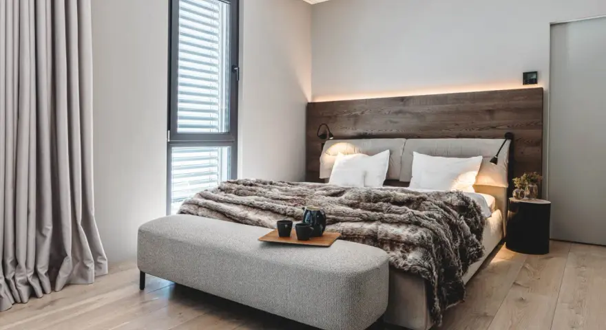 Gemütliches Schlafzimmer mit Holzbettkopfteil, flauschiger Decke und Sitzbank. Tolle zimmer inspo für ein modernes Ambiente.