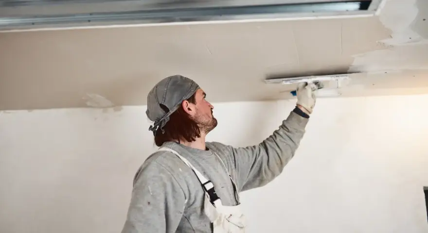 Handwerker verputzt Decke, inspiriert von modernen Deckenverkleidung Ideen für ein glattes Finish.