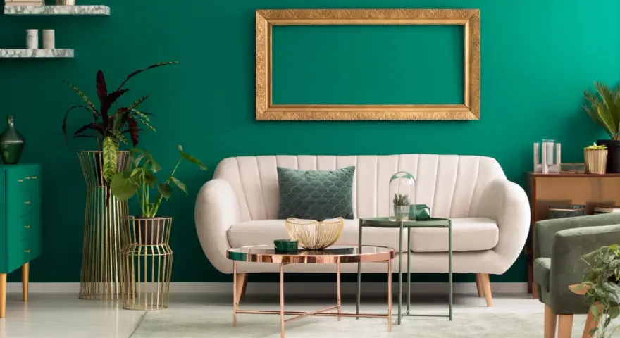 Ein helles Sofa und goldene Akzente harmonieren perfekt mit der petrolfarbenen Wand. Welche Farbe passt zu petrol? Hier sehen wir eine elegante Kombination.