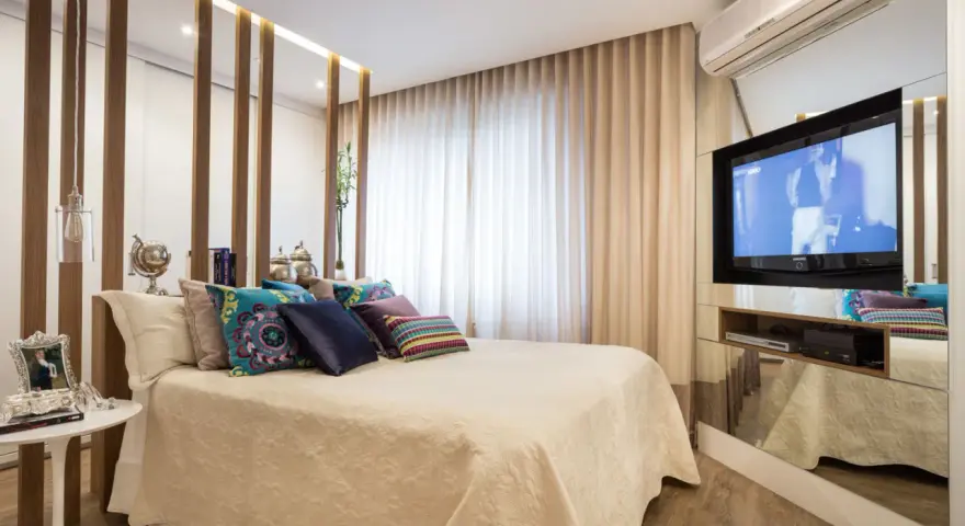 Ein modernes Schlafzimmer mit einem eleganten Bett, vielen Kissen und einem versteckten TV im Spiegel-Schrank.