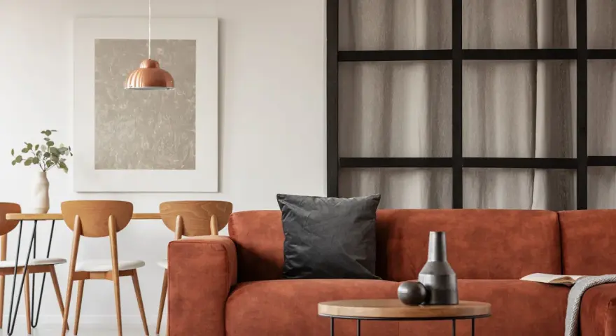 Gemütliches Wohnzimmer mit orangefarbenem Sofa, Holztisch und Stühlen. Tolle inneneinrichtung ideen für ein warmes Ambiente.