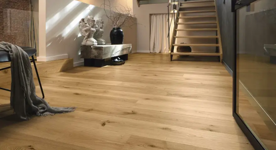 Ein heller Flur mit Treppe und Sitzbank. Der Boden ist aus echtem **Vollholz**, das Wärme und Natürlichkeit ausstrahlt.