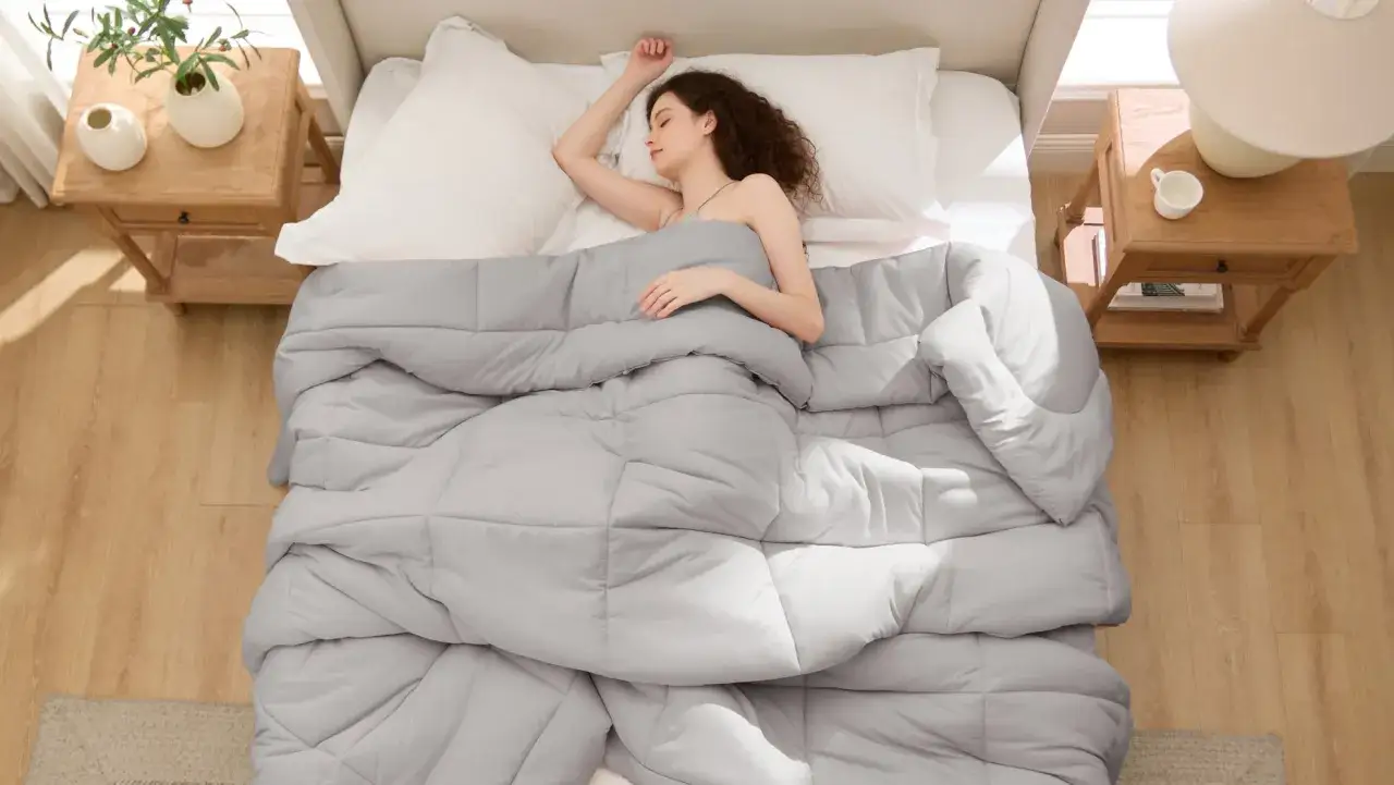 Frau schläft tief unter einer grauen Decke. Die ideale schlafzimmer temperatur sorgt für erholsamen Schlaf.