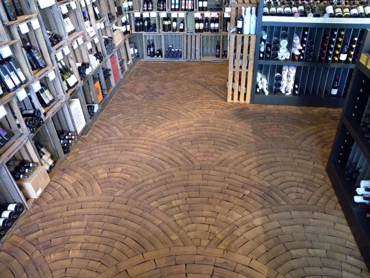Ein Weinladen mit Regalen voller Flaschen und einem Boden aus Hirnholz, das wie ein Mosaik aus Holzscheiben verlegt ist.