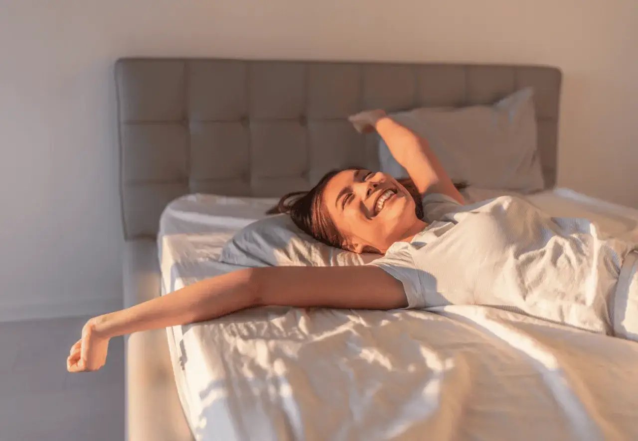 Gl&uuml;ckliche Frau streckt sich im Bett. Ob auf einem federkern oder kaltschaum, sie genie&szlig;t den Morgen.