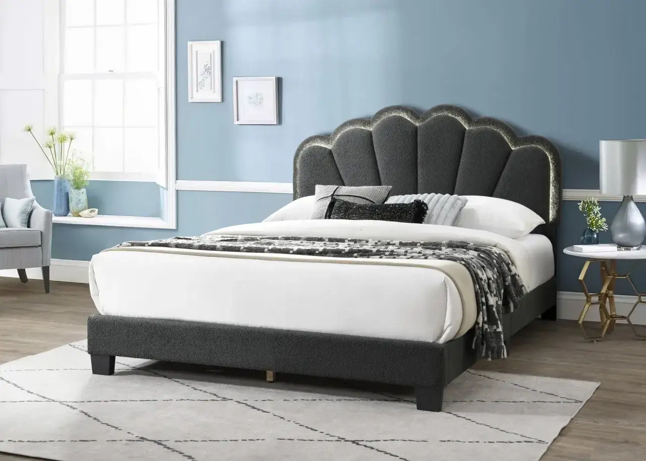 Stilvolles Schlafzimmer mit grauem Boxspringbett, das mit einer Muschel-förmigen, beleuchteten Kopfstütze und einem gemusterten Überwurf dekoriert ist.